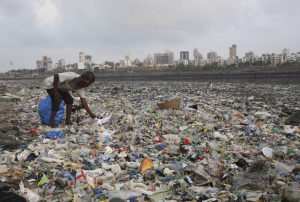 A man collects plastic and other recyclable material from the shores of the Arabian Sea, littered with plastic bags and other garbage, in Mumbai, India, Monday, June 4, 2018. The theme for this year's World Environment Day, marked on June 5, is "Beat Plastic Pollution." (AP Photo/Rafiq Maqbool)